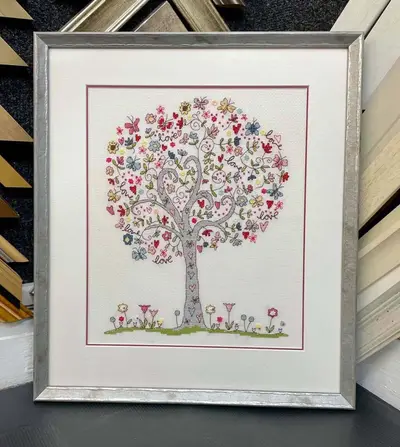 Embroidered tree of hearts in a silver frame with a white mount framed by Tripps of Keynsham