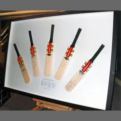 Five signed miniature cricket bats in a white box frame framed by Tripps of Keynsham