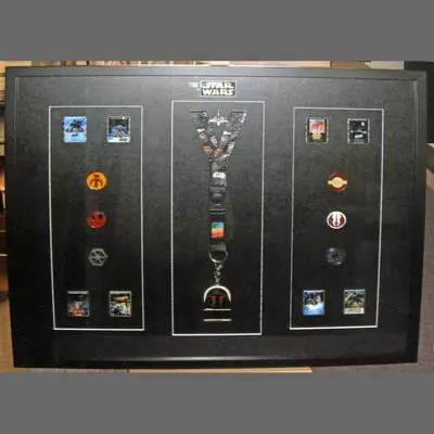 Pin badges and keepsakes arranged on a black mount framed by Tripps of Keynsham