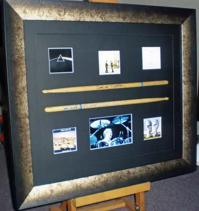 Film memorabilia and drumsticks framed on black framed by Tripps of Keynsham