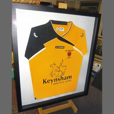 Yellow Keynsham football shirt in a black box frame framed by Tripps of Keynsham